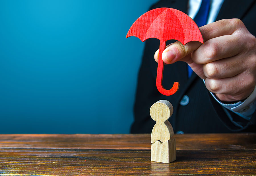 Photo illustrant la main d'un homme tenant un parapluie en bois rouge au-dessus d'un petit personnage en bois